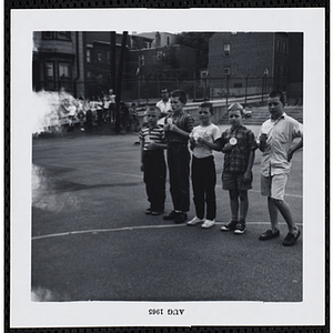 A group of five boys hold number cards on a playground at a carnival