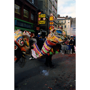 Performance of the dragon dance in the street while a large crowd watches