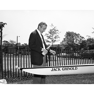 Jack Grinold stands with champagne over a crew shell named in his honor