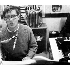 Young man speaking into a microphone in the broadcast booth at the WNEU studio