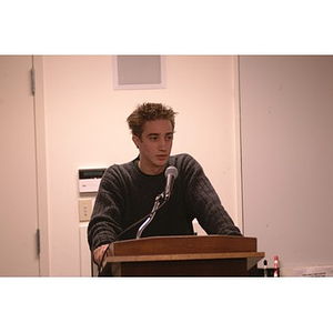 A young man giving a speech to the Student Senate during a meeting of the Student Government Association