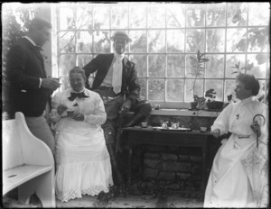 Two men and two women drinking tea in greenhouse