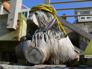 Tree-stump carved like a bear, sitting next to a wooden deck