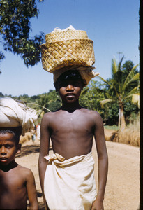 Two boys carry things on their heads