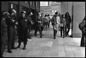 Small group of protesters file past police at the entrance to the John F. Kennedy Federal Building