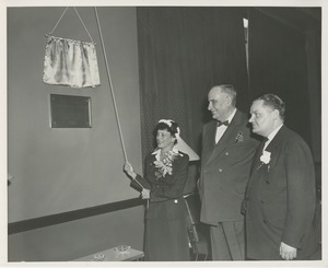 A woman unveils the newman student lounge plaque