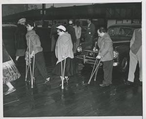 People using crutches cross parking lot