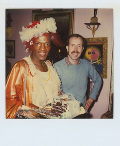 A Photograph of Marsha P. Johnson Wearing a White and Orange Dress While Holding a Cake