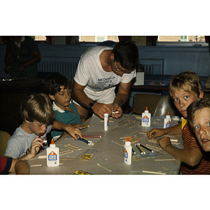 Boys seated around table making crafts with popsicle sticks