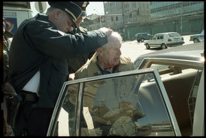 Elderly man with bloodied head (Wilfrid Lapierre) being arrested and put into patrol car by two policemen after protesting the banking crisis