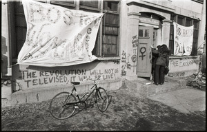 Women's occupation of the Architectural Technology Workshop, Harvard University: two women entering occupied building; banner for "Boston Women's Center" and graffiti "The revolution will not be televised, it will be live!"