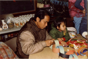 Photograph of a man making decorations during a Christmas and New Year celebration, [1982-1983].