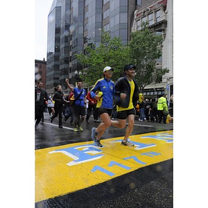 Runners approach the "One Run" finish line in front of Marathon Sports in Copley Square