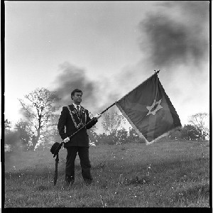 Rev. Hugh Ross, political activist and leader of the Independent Ulster Movement, posing with flag of IUM.