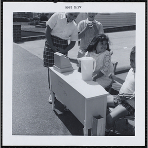 A girl and a boy selling beverages at a Boys' Club Freckle King Contest