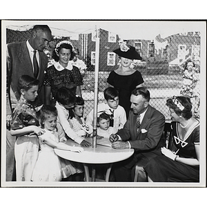 "Arthur Curren, Jr., President of Boston Rotary Club and Mrs. Curren signing up Boys' Club Day Campers for the 'Little Sister Contest' while judges Mr. and Mrs. Forrester A. Clark (Pres. of Boys' Club of Boston) and Carole Bridge (Allen Model Agency) look on"