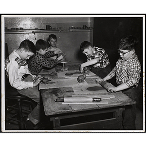 Five boys sit and stand around a table, working on projects for their pottery class at the Boys' Clubs of Boston