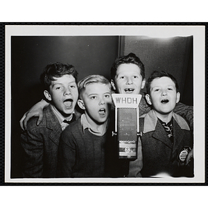 Four boys sing into a WHDH studio microphone