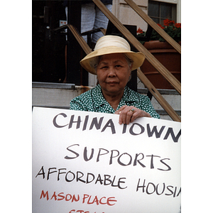 Elderly Chinese-American woman holds a poster reading, "Chinatown supports affordable housing"