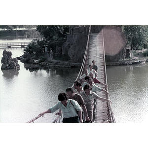 Association members walk on a rope bridge