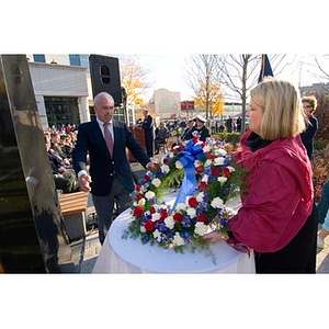 A man and woman with a big wreath at the Veterans Memorial dedication ceremony