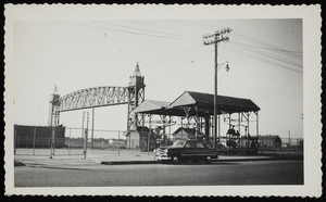 A view of a car parked on a road in front of the Cape Cod Canal railroad bridge