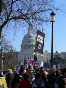 Protesters on the National Mall, marching against the War in Iraq, holding sign reading 'Impeachment: the path the justice' with the Capitol Building in the background