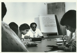 George Beatty sitting in conference room with group, discussing budget