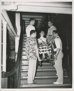 Woman in wheelchair being helped on the stairs