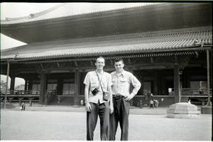 A photograph of two young men in front of Far Eastern building