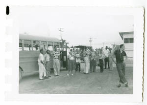 Photograph of a group of men standing with a bus