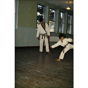 Boy practicing martial arts as an instructor looks on
