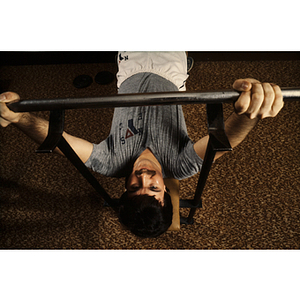 Man lifts a barbell while lying on a bench