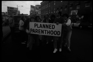 Planned Parenthood escorts with banner passing pro-life protesters in front of the Providence Planned Parenthood clinic