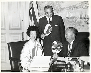 Miss Akiko, assistant to the Mayor of Kyoto, Japan, brings greetings to Mayor John F. Collins from Kyoto, with unidentified man standing behind them