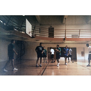 Young men playing basketball in a gym.