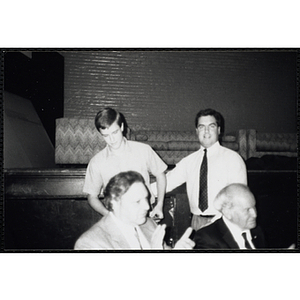 A man presents a young man with an award and looks at the camera while two others look off to the right during a Boys and Girls Club Awards Night