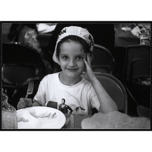 A smiling boy sitting at a table with food during a Boys and Girls Club event