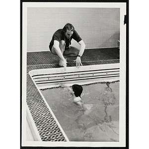 A man instructs a girl swimming in a natatorium pool