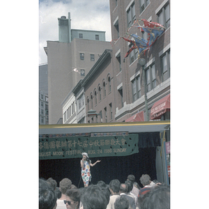 Woman addresses a crowd from a stage at the August Moon Festival in Boston's Chinatown