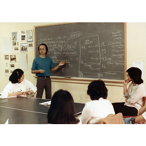 Students in a job placement course sit at a large table, watching their teacher