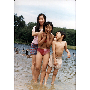 Small boy stands with two girls in a lake