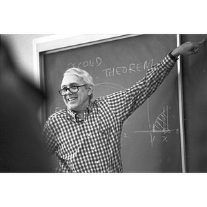 Professor Robert Case smiles in front of a chalkboard