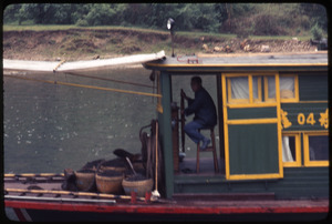 Fisherman at wheel of boat, green and yellow