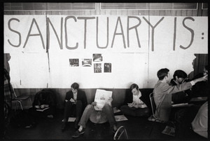 Protesters at the Sala de Puerto Rico seated under banner reading 'Sanctuary is' : Vietnam War sanctuary at MIT