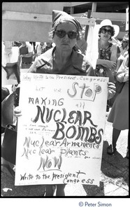 Woman at the Mobilization for Survival antinuclear demonstration near Draper Laboratory, MIT, carrying a sign reading 'Let us stop making nuclear bombs'