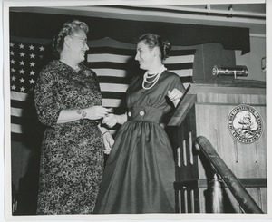 Unidentified woman handing gift to client at graduation exercises