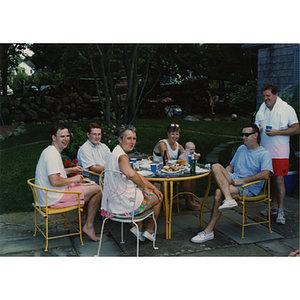 Three men and two women with a baby seated around a table while a man stands beside them at a Boys and Girls Club Board outing