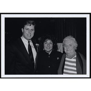 A man and two women posing for the camera at a St. Patrick's Day Luncheon