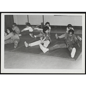 Children perform stretches on mats